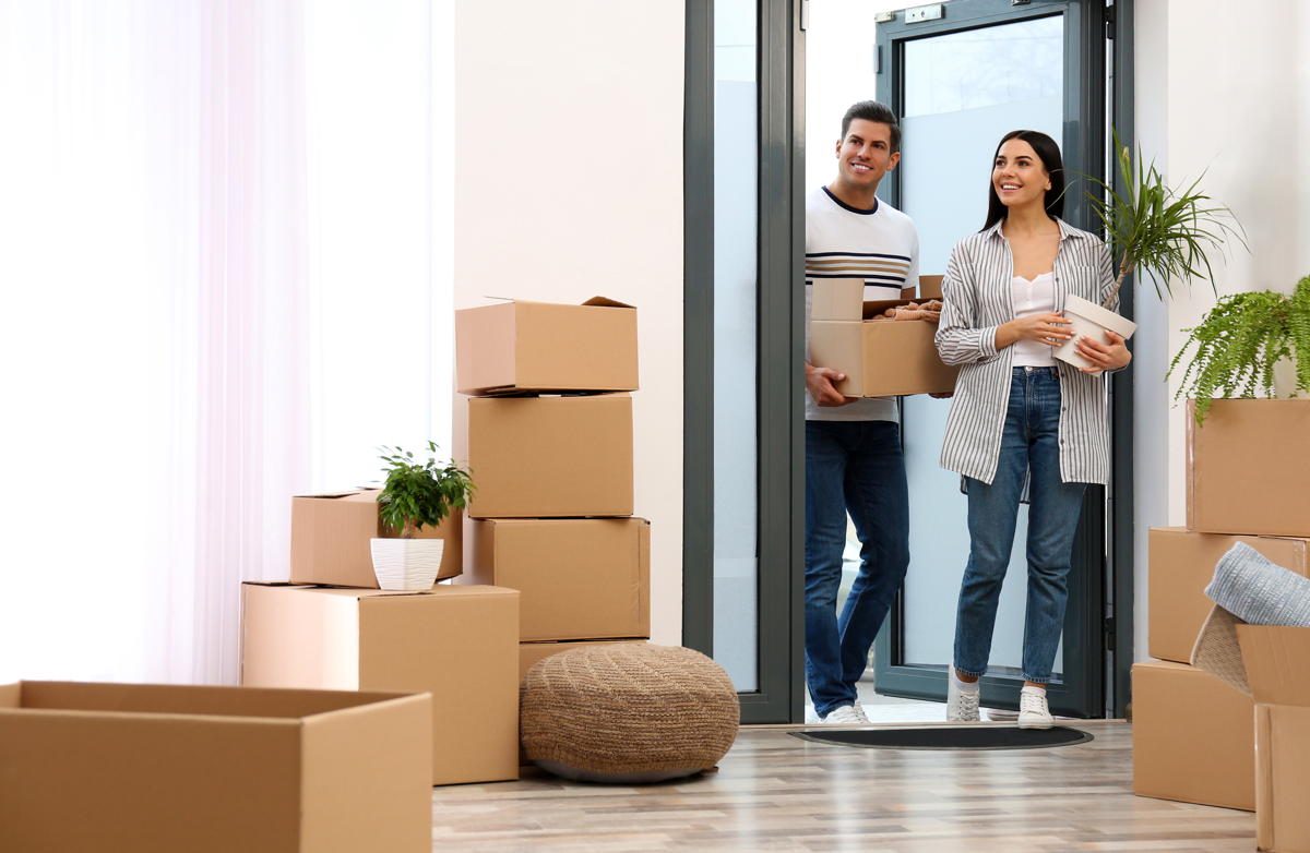 Happy couple entering their new flat with moving boxes